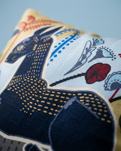 Decorative pillow with cornish rex cat design on a light blue background